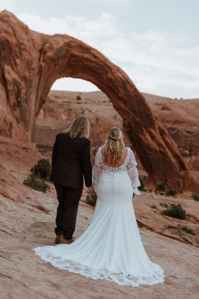 couple poses under arch at Bureau Land Management land