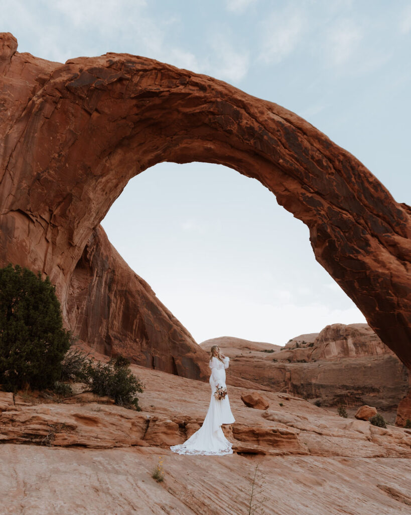 bride poses under arch at Arches National Park elopement