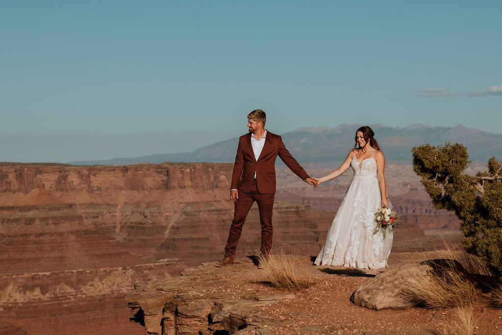 couple stands at overlook at outdoor Moab desert elopement