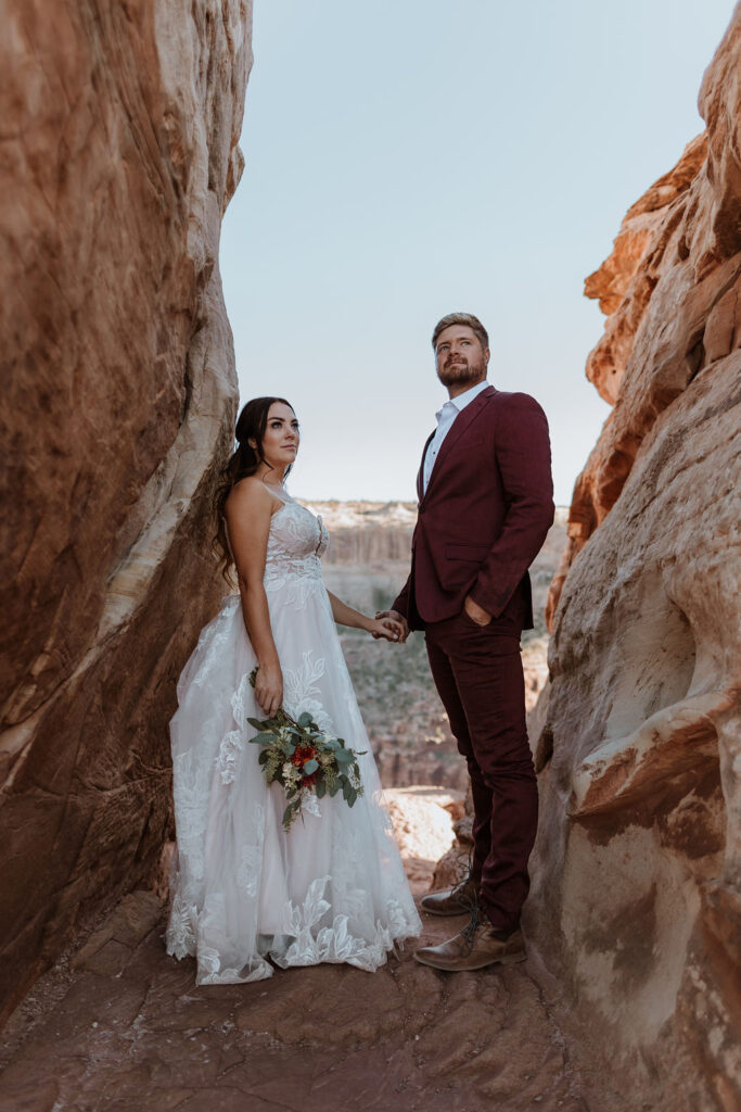 couple holds hands on overlook at Canyonlands National Park elopement