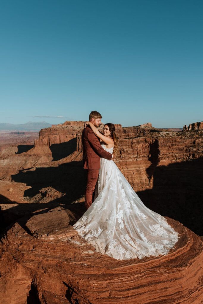 couple holds hands on rock at Moab elopement