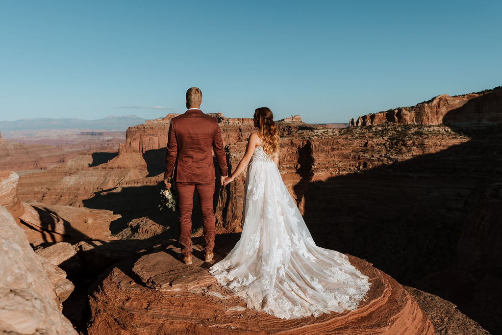 couple holds hands on overlook at Canyonlands National Park elopement