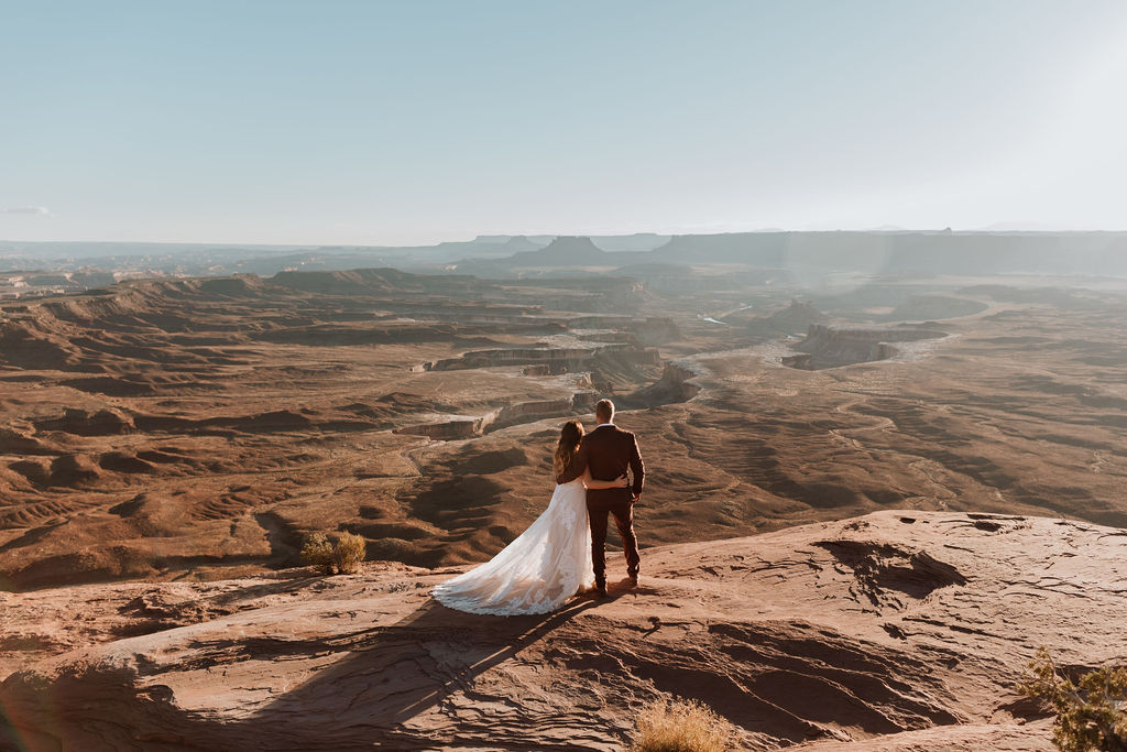 couple holds hands on overlook at Canyonlands National Park elopement