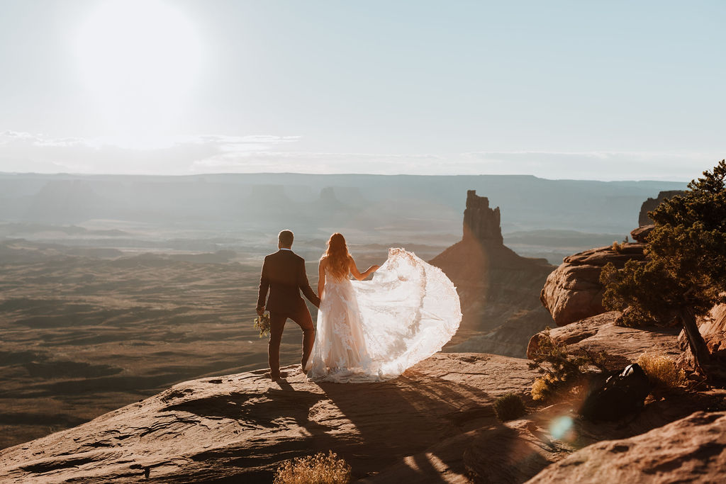 couple stands at overlook at outdoor Moab desert elopement