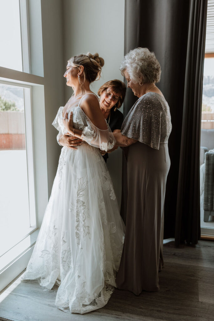 bride has help putting on wedding dress