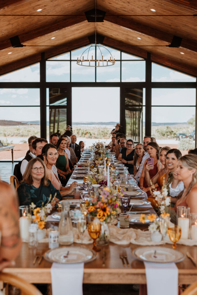 wedding guests sit at long table 