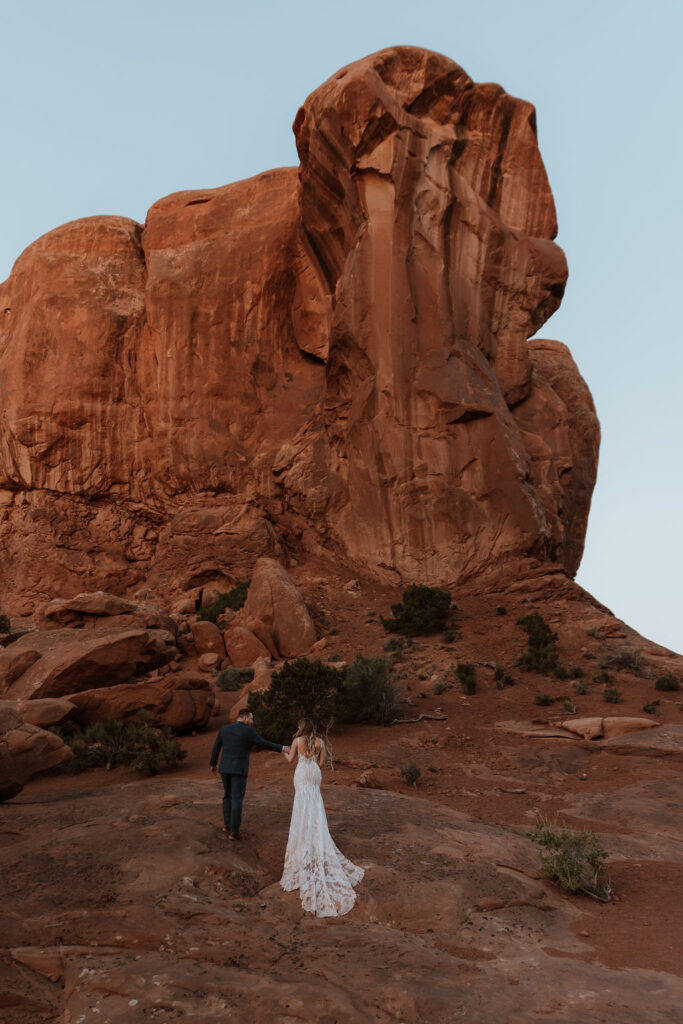 couple walks along arches at outdoor Moab desert elopement