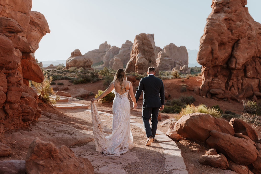 couple walks along path at Arches National Park elopement