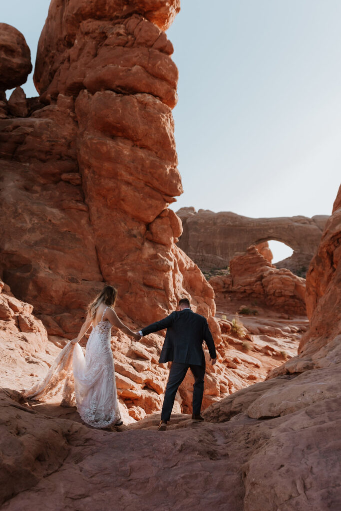 couple walks along arches at outdoor Moab desert elopement