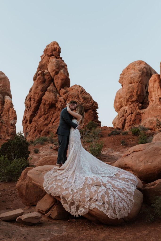 couple stands against red rocks at outdoor Moab desert elopement