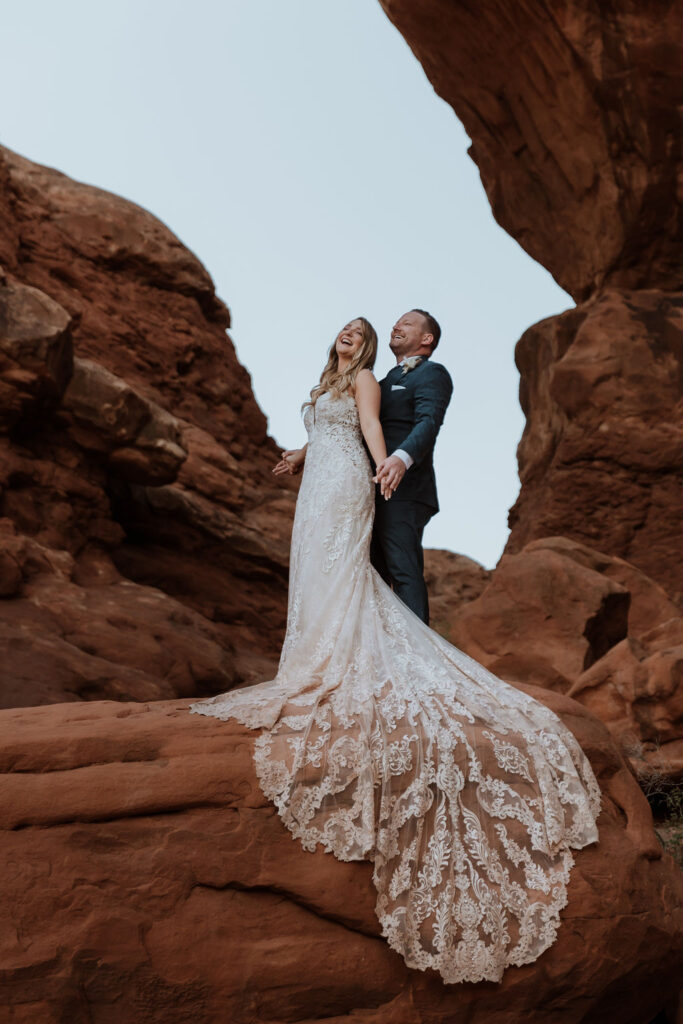 couple stands under arch at Arches National Park elopement