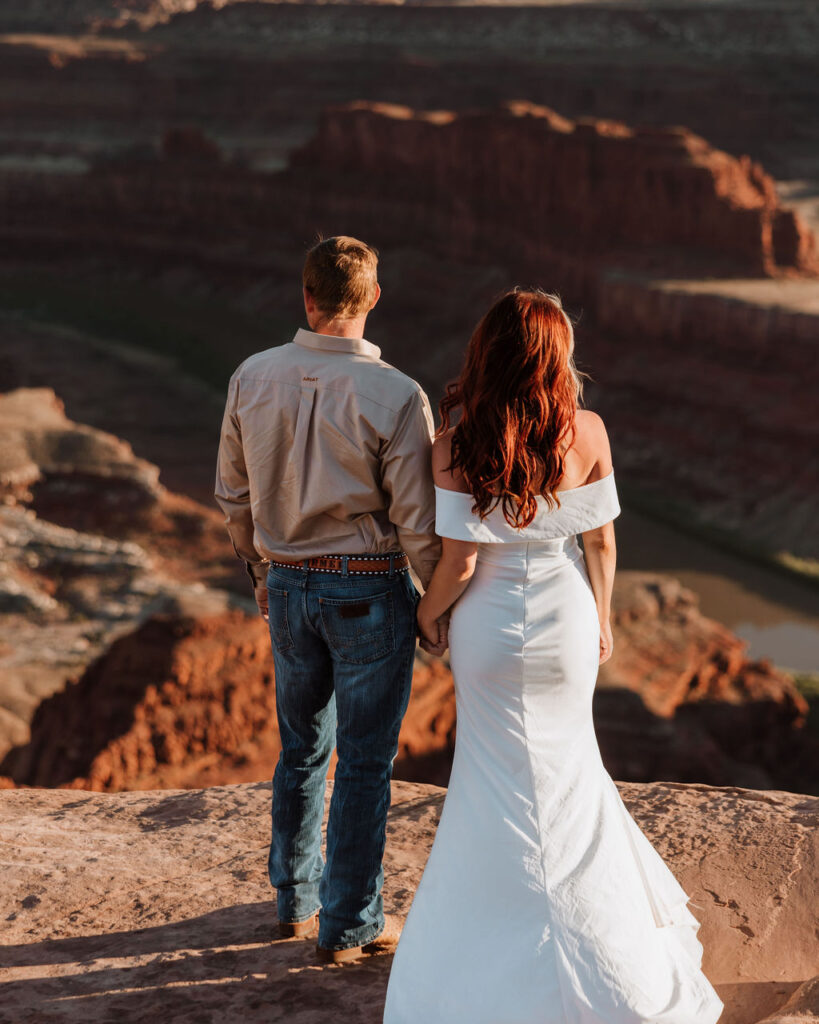 couple holds hands at Moab sunset overlook