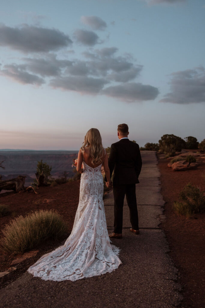 couple walks holding hands at Moab sunset elopement