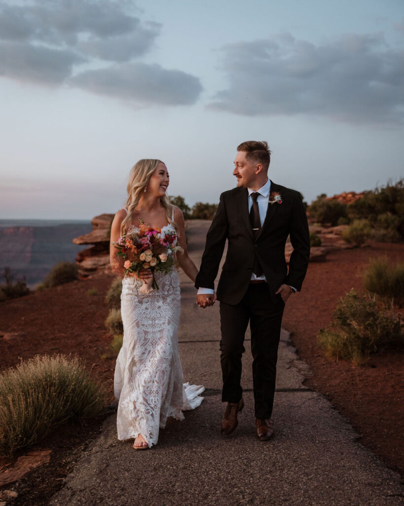 couple walks holding hands at Moab sunset elopement