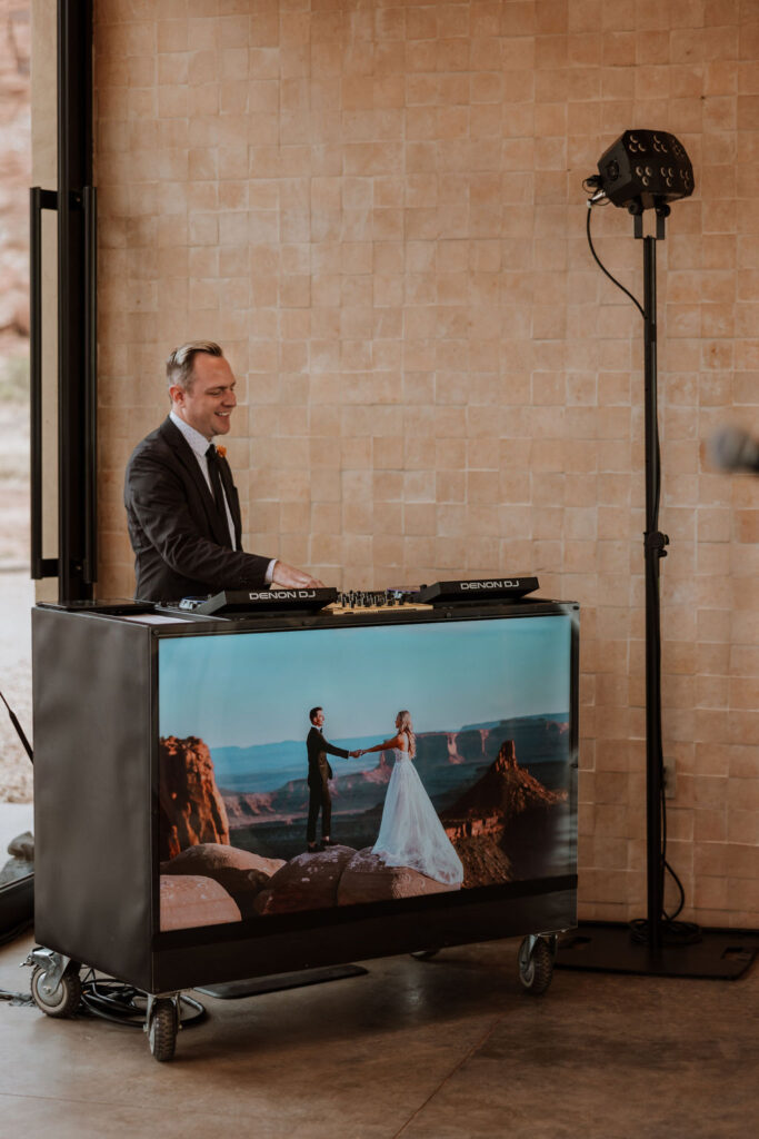 DJ plays music with couple's wedding photos on booth