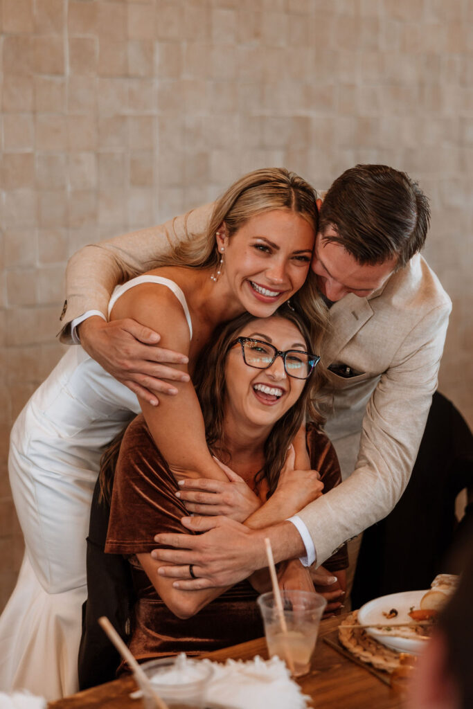 couple embraces wedding guest at reception