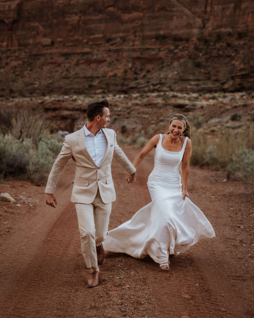 couple runs holding hands at Moab elopement
