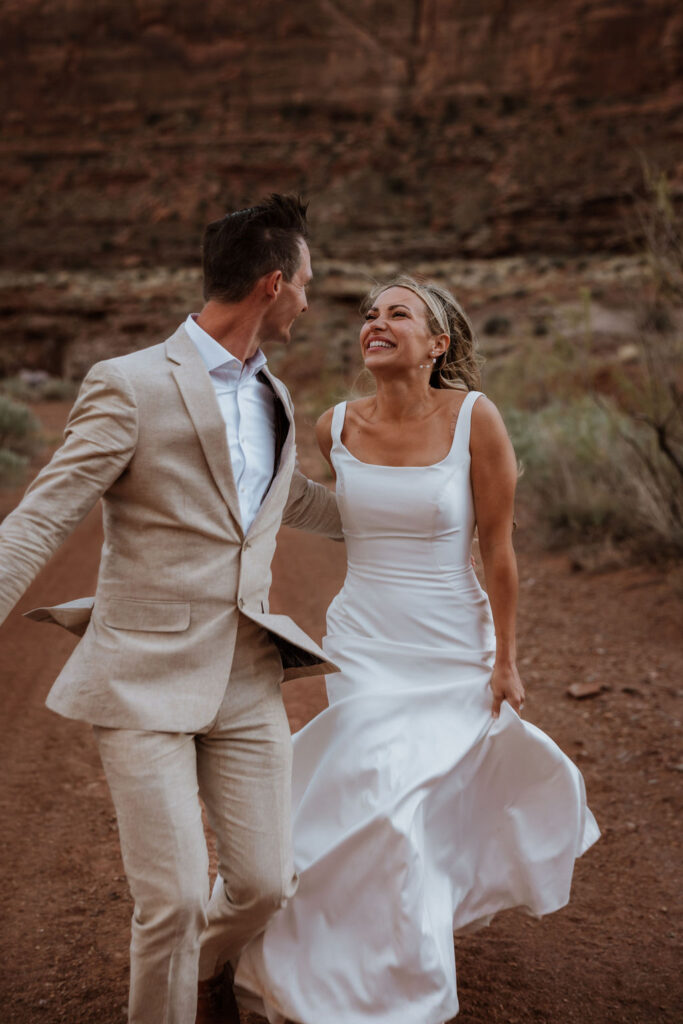 couple runs together at Moab elopement
