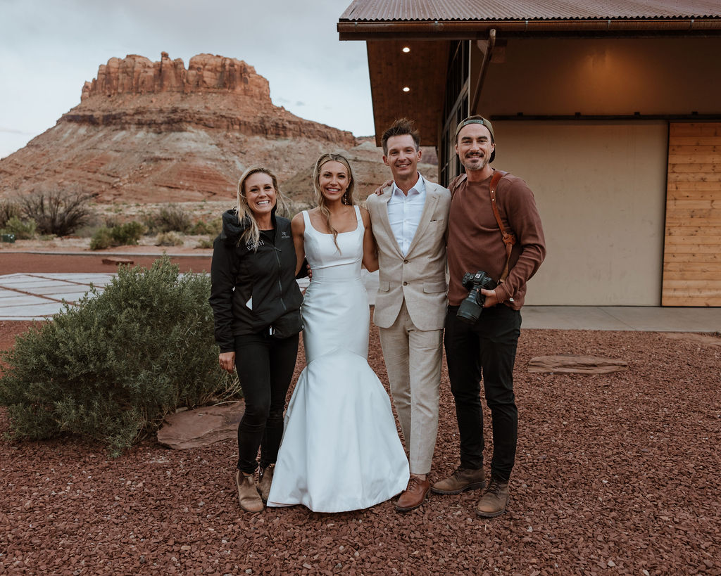 Moab wedding photographer poses with couple at Red Earth Venue wedding