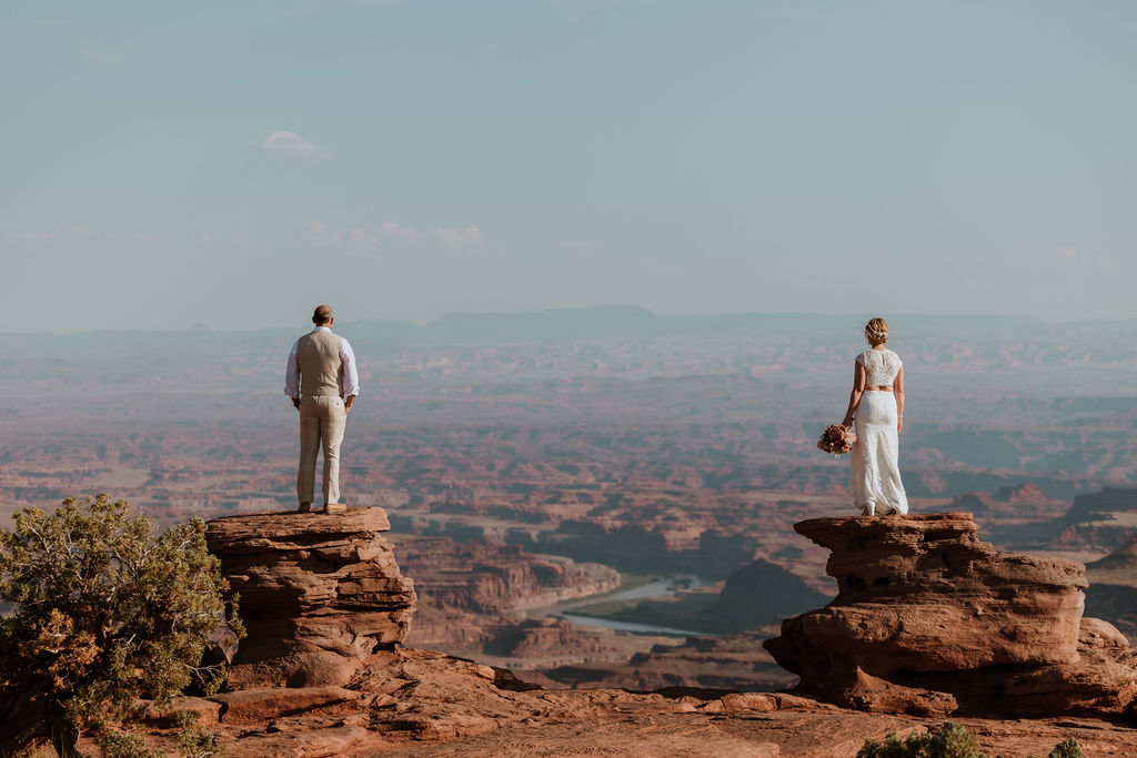 couple stands on edge at Moab overlook