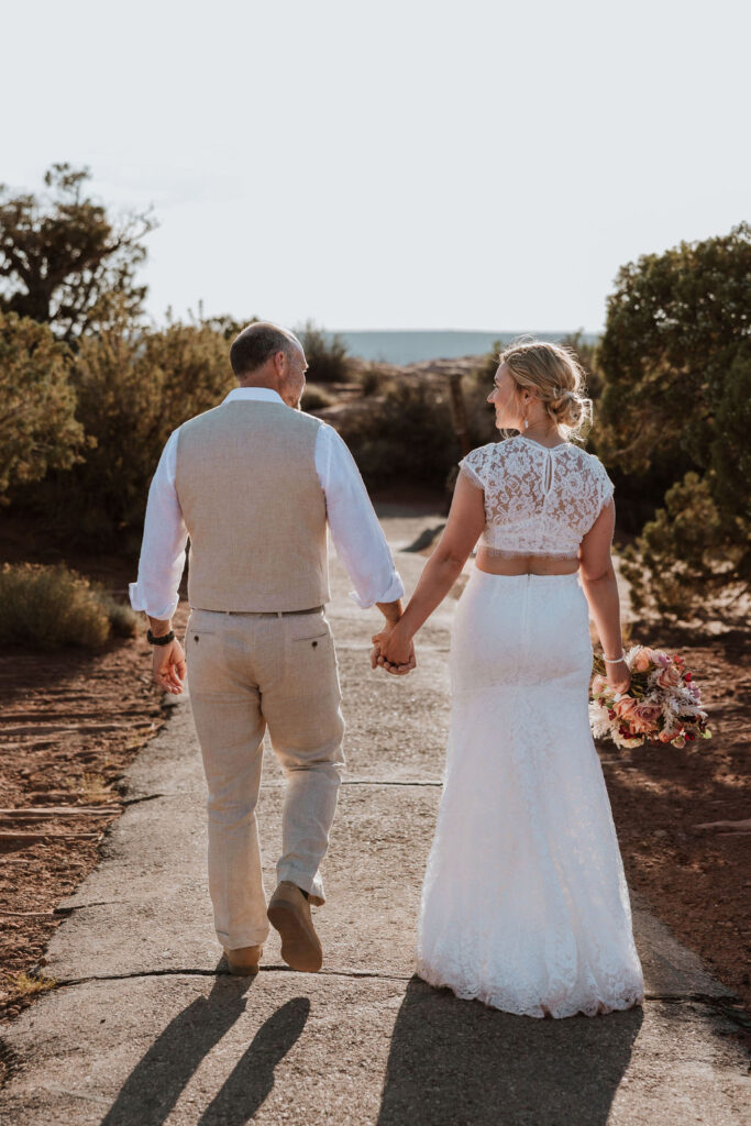 couple walks holding hands at Moab wedding