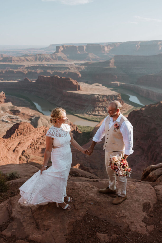 couple holds hands at Moab overlook