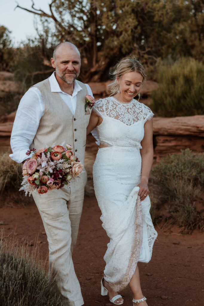 couple walks along Utah landscape at Moab wedding