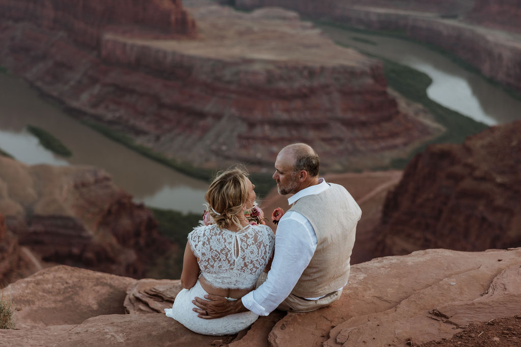 couple sits on overlook at Moab wedding