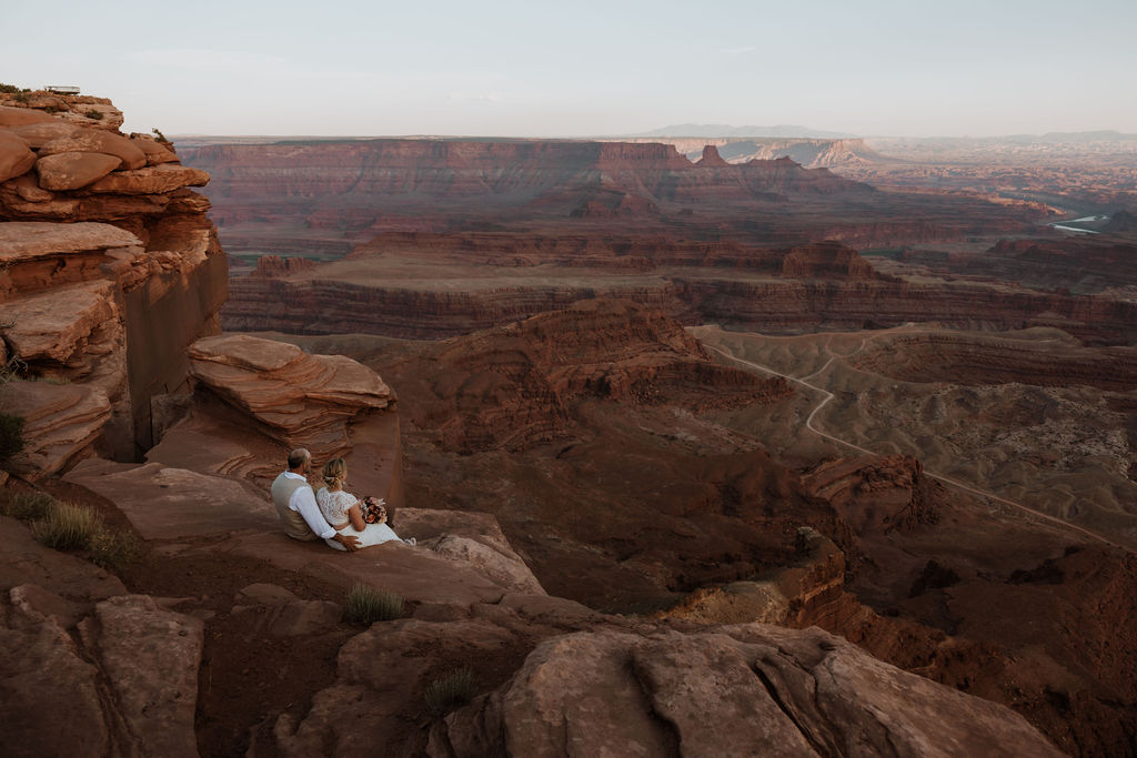 couple sits on overlook at Moab wedding