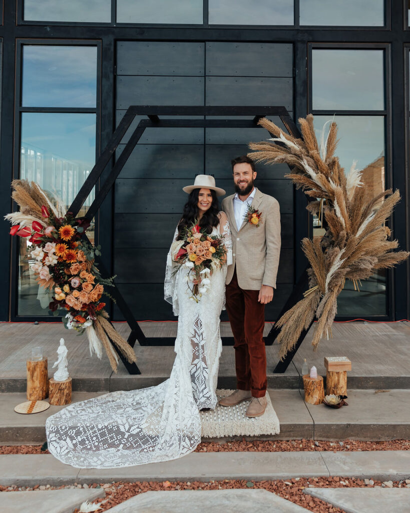 couple poses under wedding arch at Red Earth Venue wedding