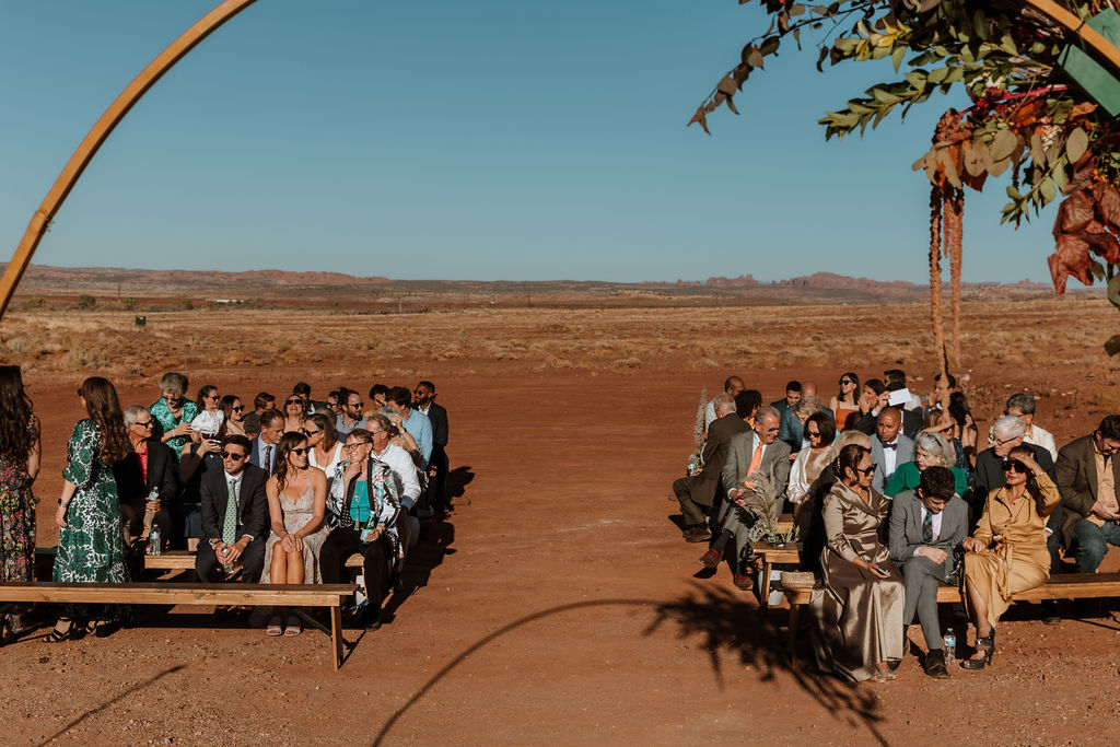 guests sit on benches at Red Earth Venue wedding