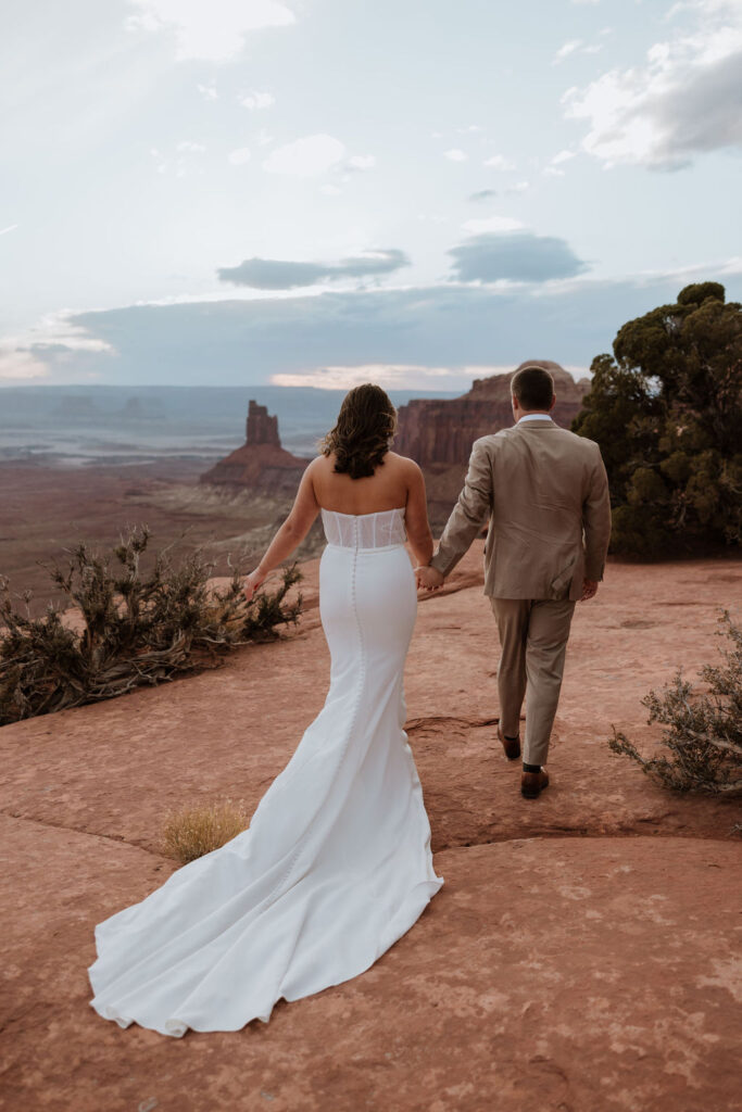 couple walks holding hands at Canyonlands elopement