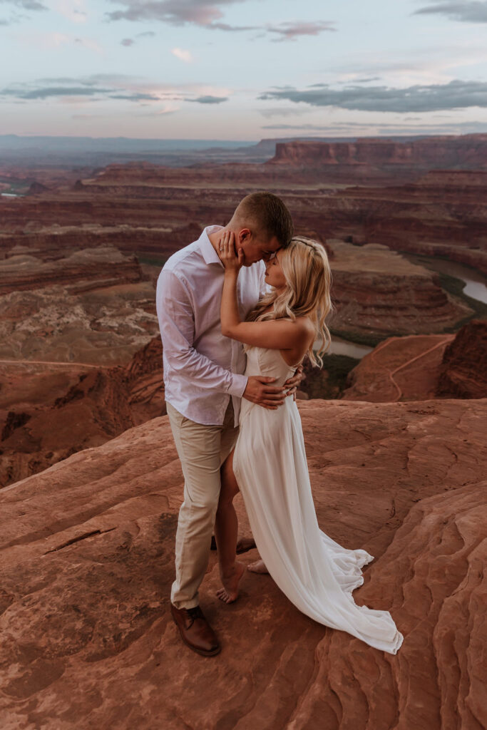 couple embraces on overlook at Dead Horse State Park elopement