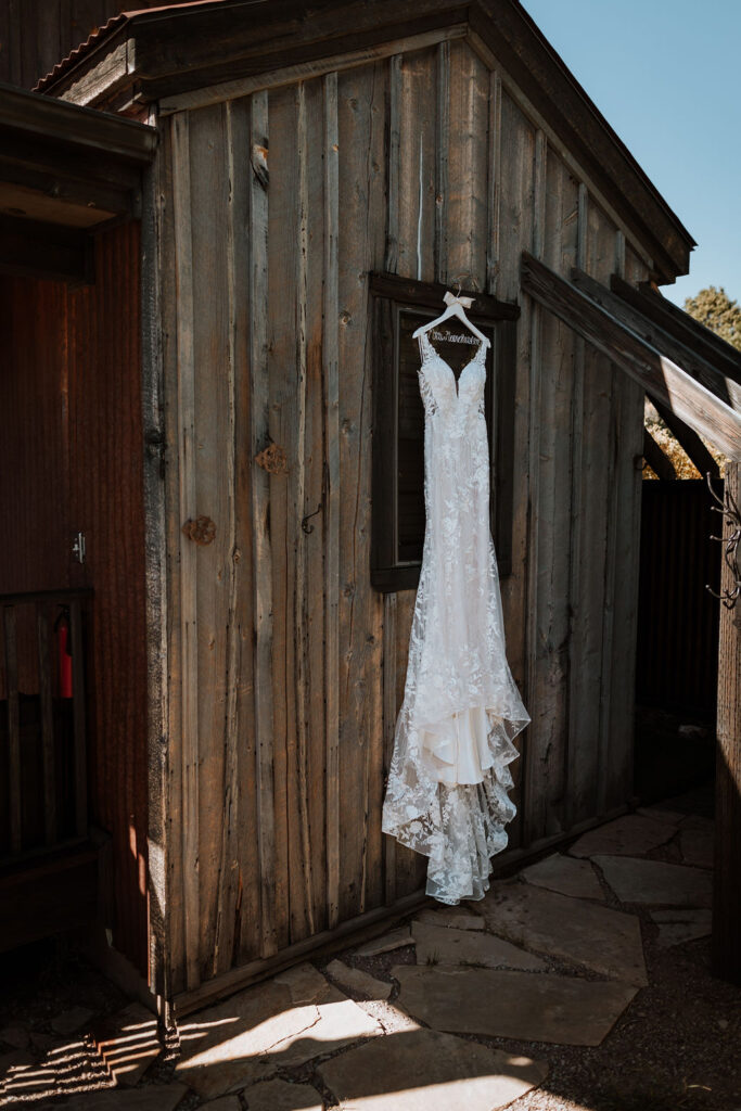 wedding dress hangs on barn wall