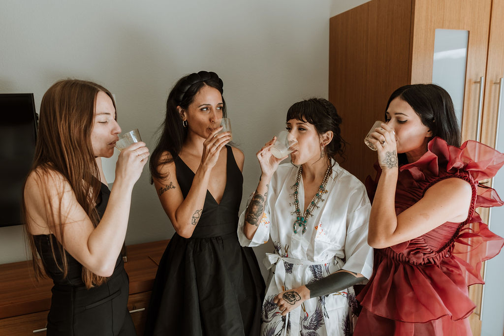 bride drinks with bridesmaids during wedding getting ready