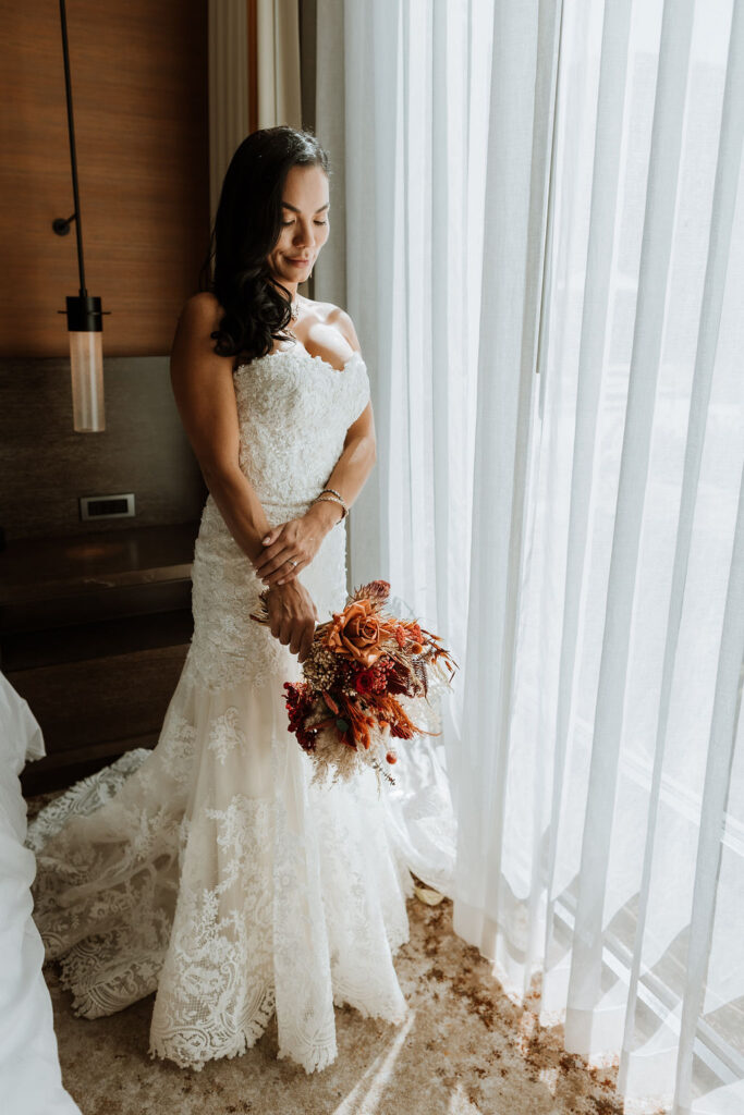 bridal portraits at hotel window with wedding bouquet 