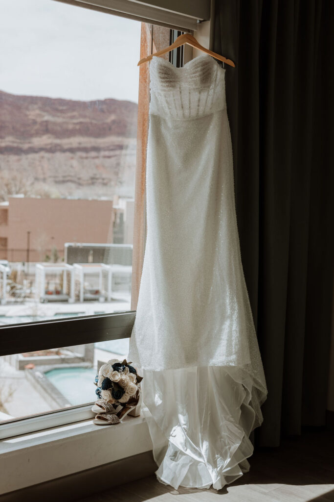 wedding dress hangs on window at top where to stay in Moab location