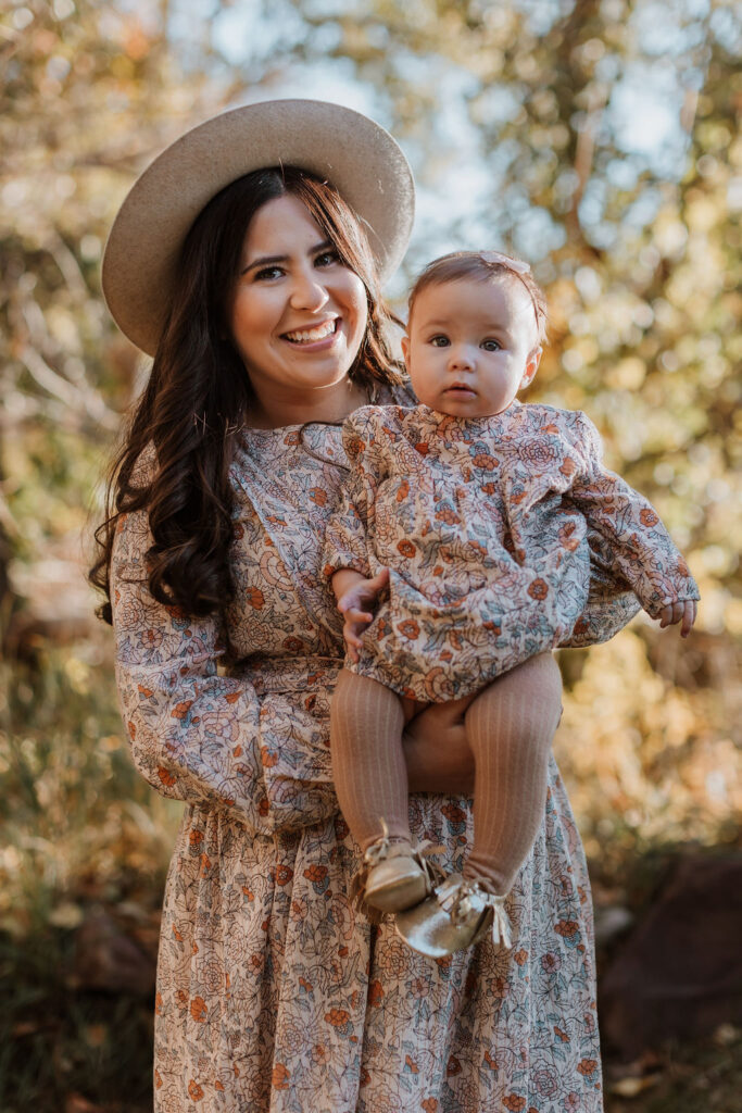 mom holds baby newborn wearing matching dresses