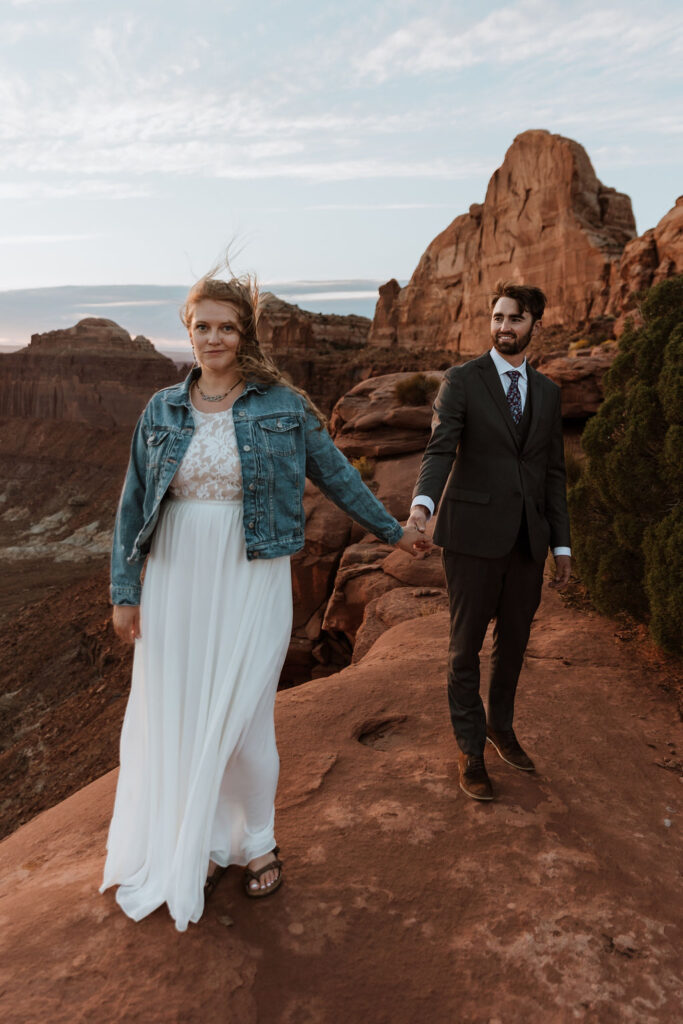 couple holds hands at windy Canyonlands National Park elopement