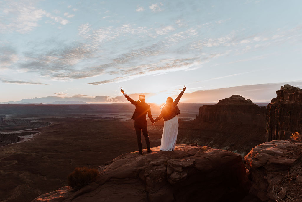 couple stands on overlook at sunset Canyonlands National Park elopement