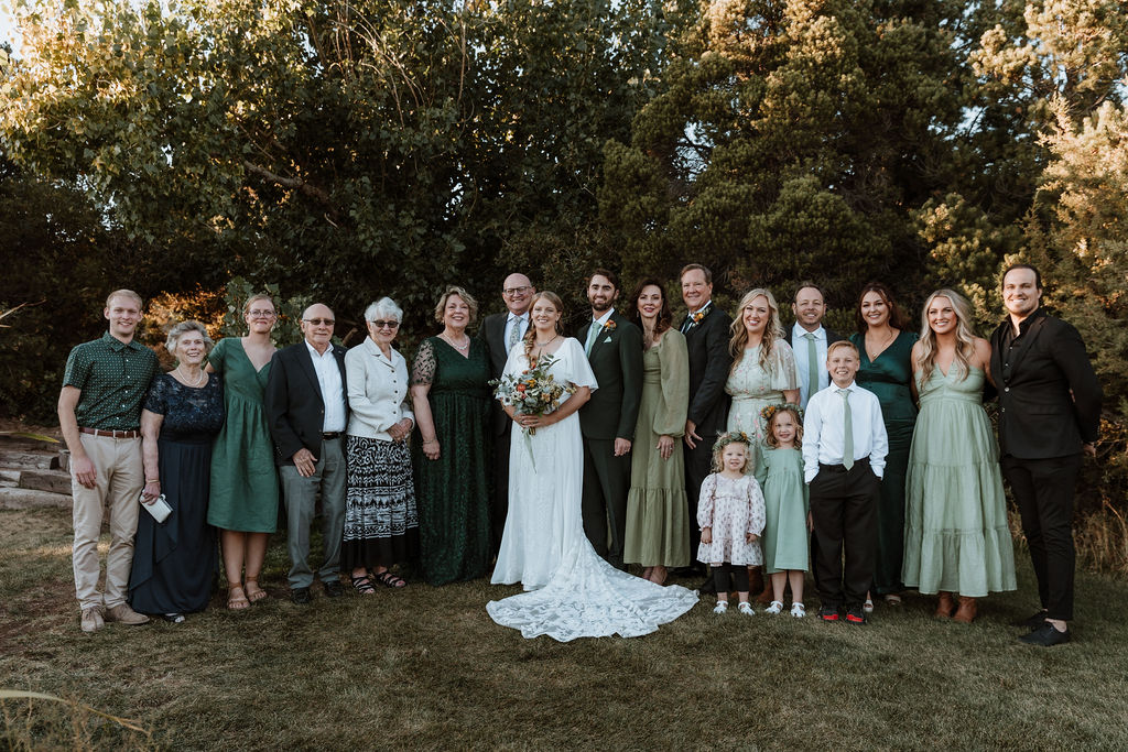 couple poses with family at outdoor forest wedding in Utah