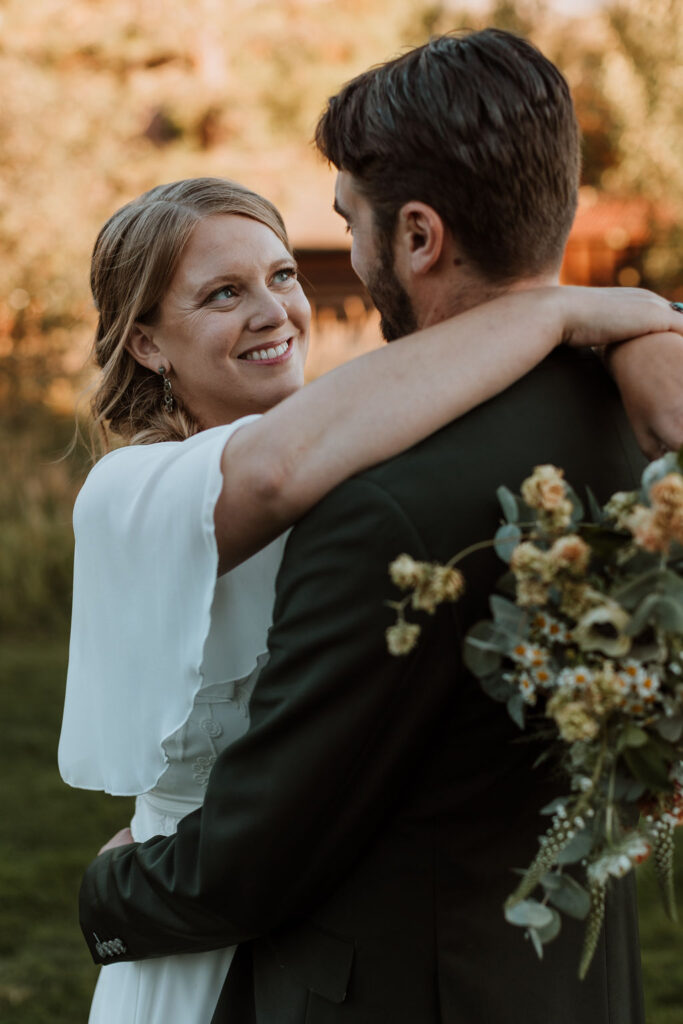 couple embraces holding wildflower wedding bouquet 