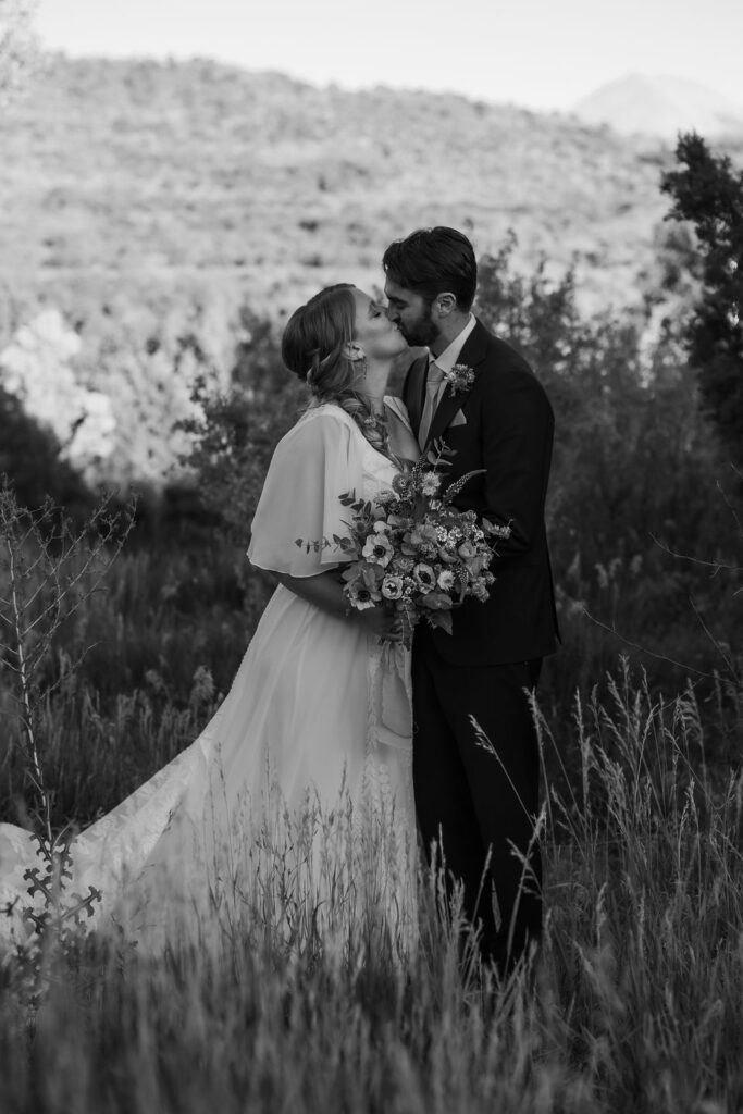 couple kisses in meadow at Whispering Oaks Ranch sunset wedding