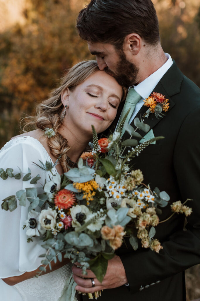 couple embraces holding wildflower wedding bouquet 