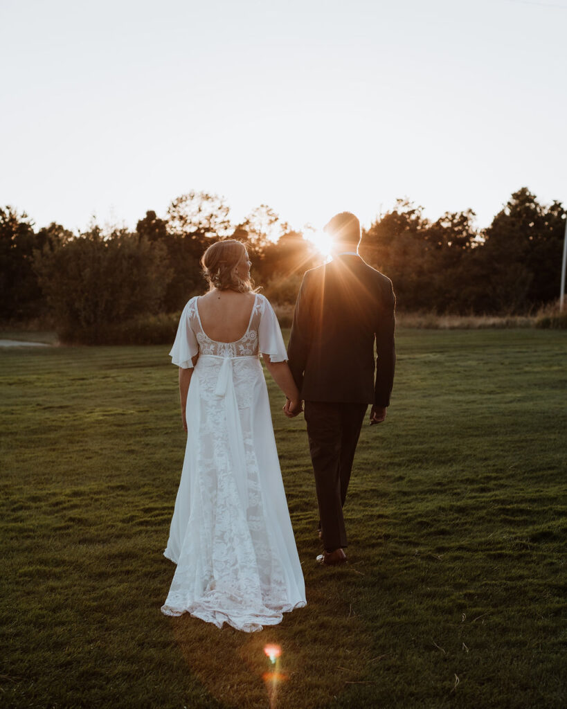 couple walks along field at sunset outdoor elopement