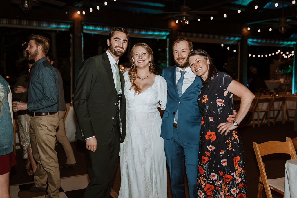 couple poses with guests during wedding reception