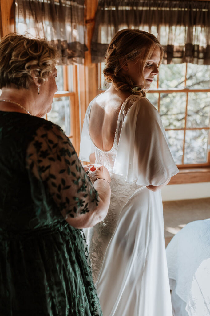 mother of bride zips up wedding dress