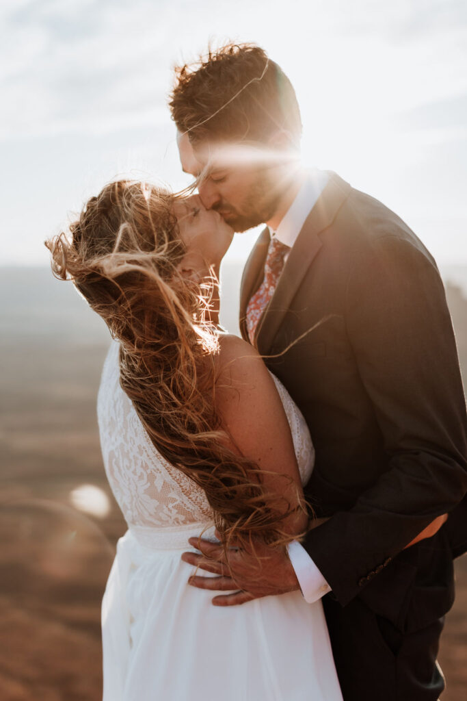 couple kisses at windy Canyonlands National Park elopement