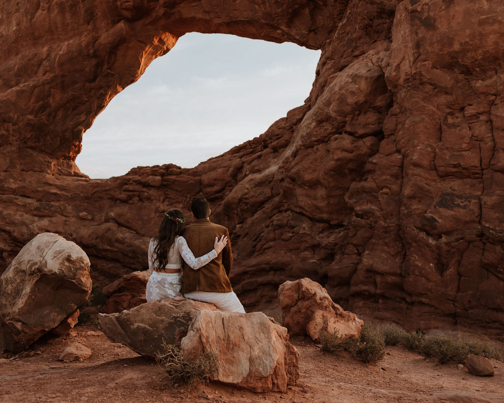 couple sits together at Arches National Park elopement