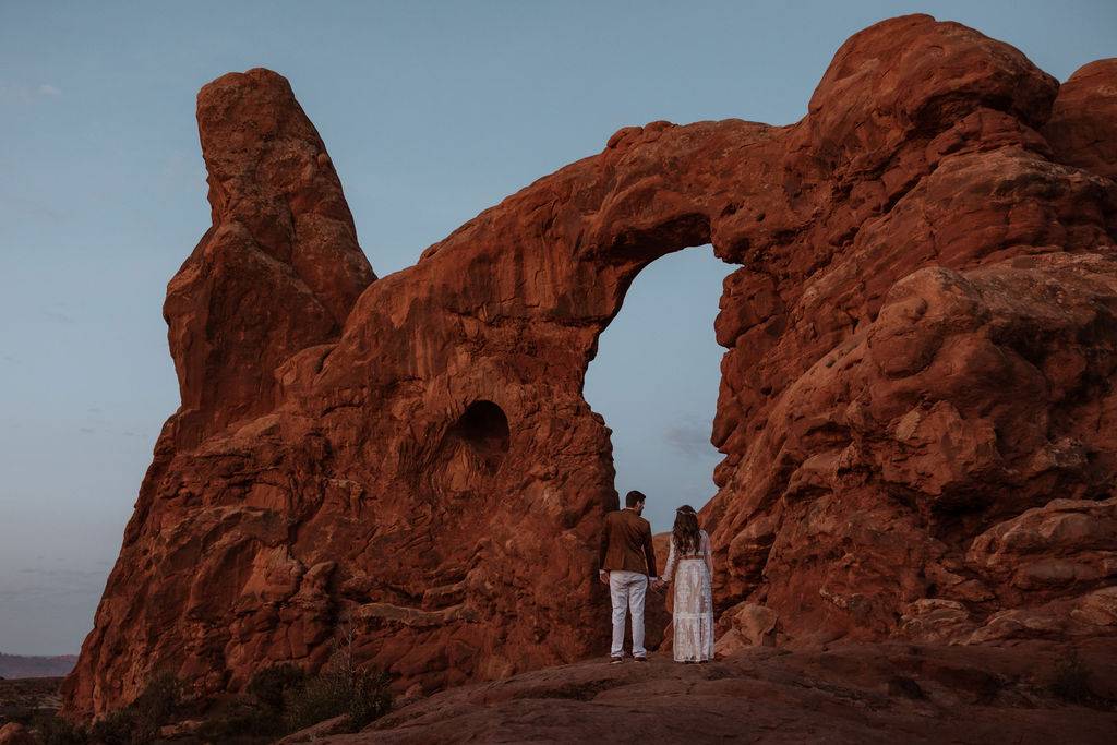 couple holds hands at Arches National Park sunset elopement